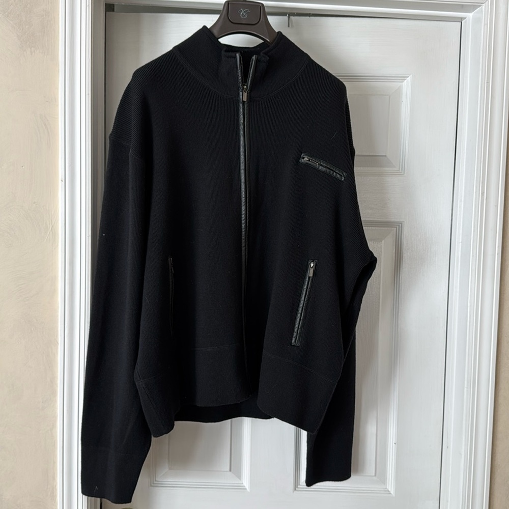 Black 100% merino wool with leather trim from zipper and front pockets.